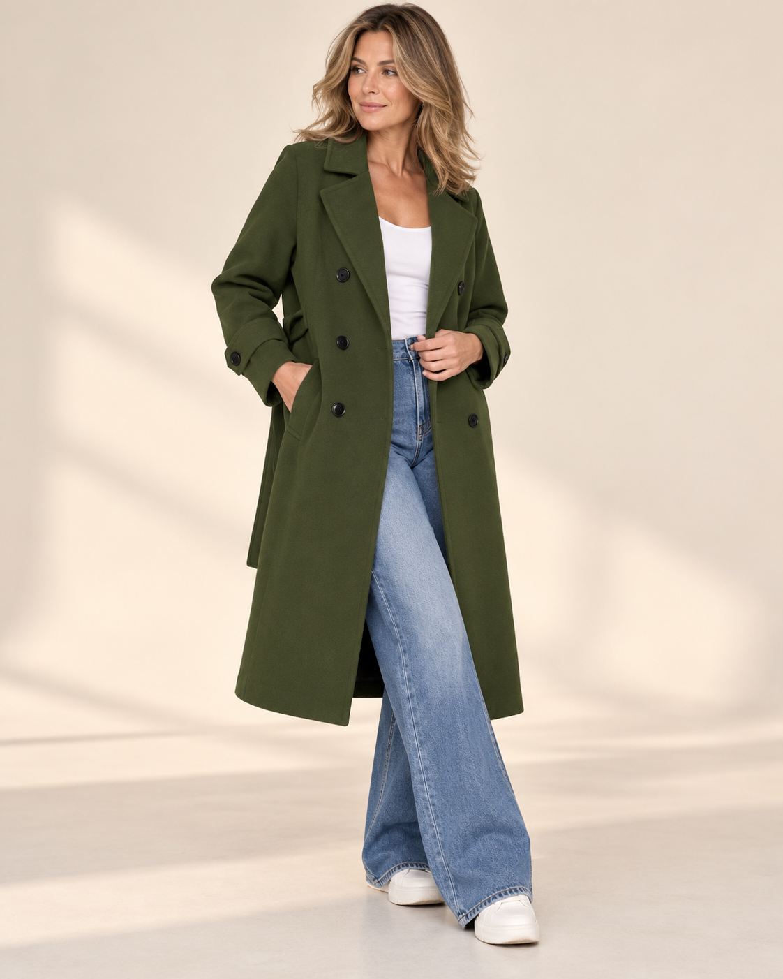 Model in a long green coat on a city balcony at night
